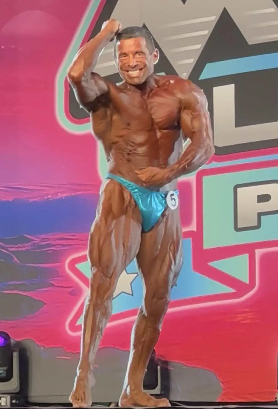 Bodybuilder posing on a stage with a colorful background