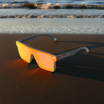 Super Style orange mirrored sunglasses resting on a sandy beach at sunset, reflecting a coastal lifestyle and modern summer fashion.