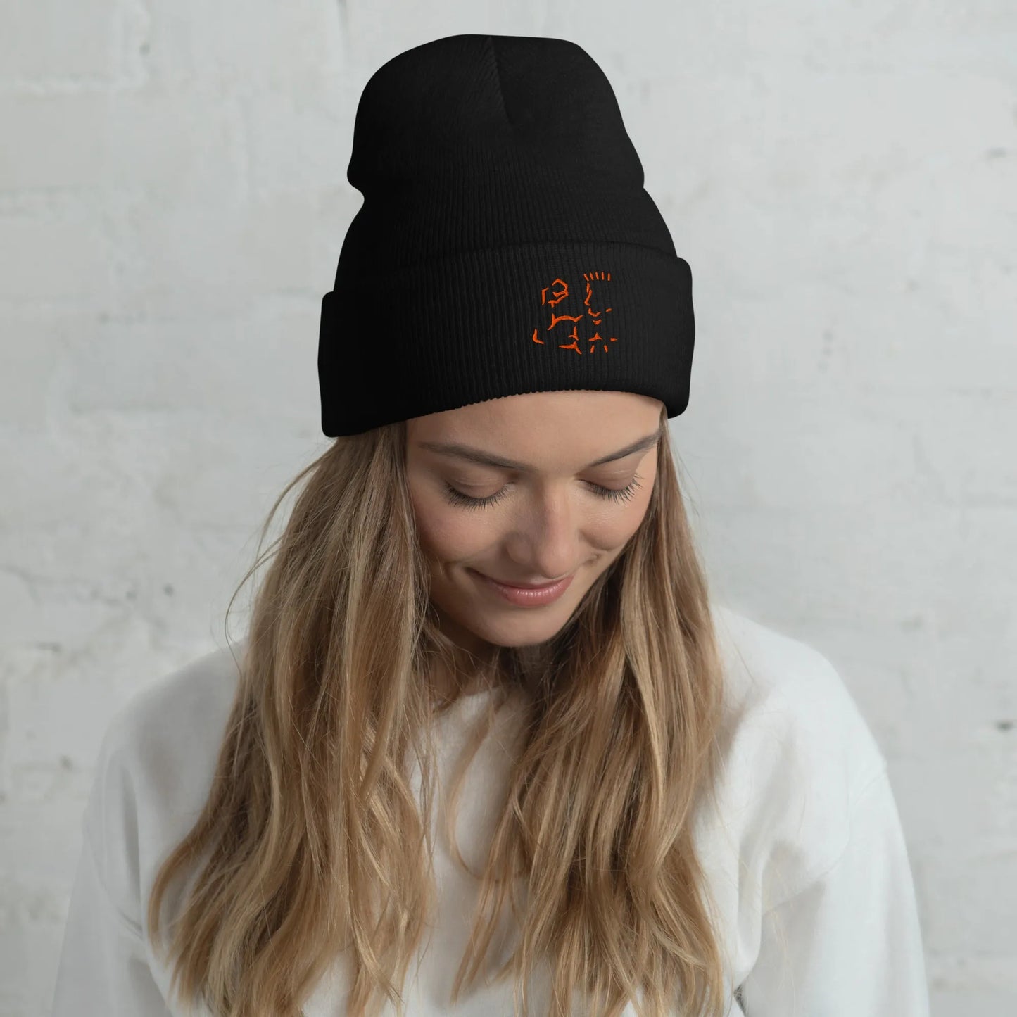 Female model wearing black Super Style cuffed beanie with orange embroidery, casual look.