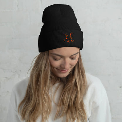 Female model wearing black Super Style cuffed beanie with orange embroidery, casual look.