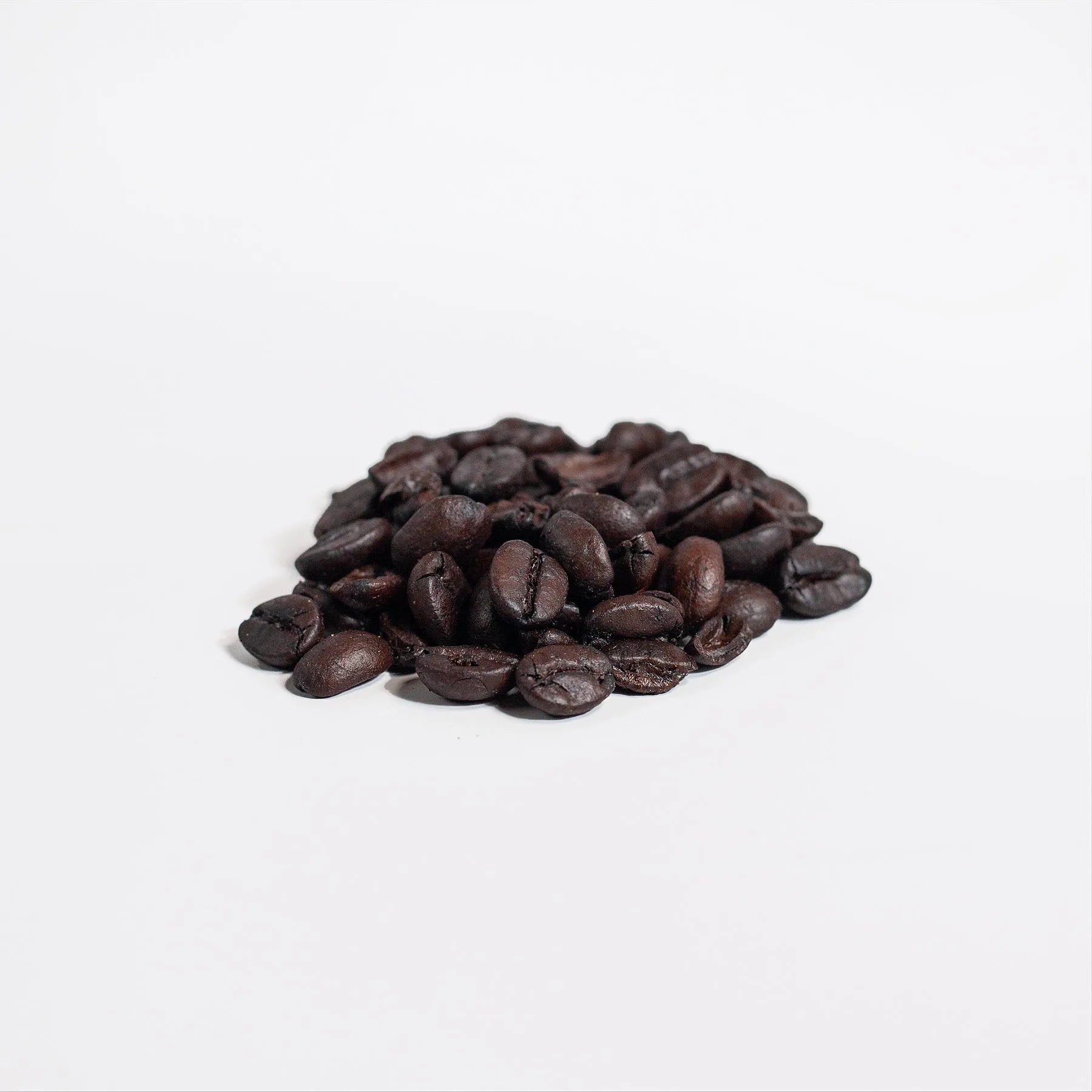 Close-up of Super Style premium roasted coffee beans on a white background, showcasing rich dark roast texture and aroma used in the Manuka Honey Coffee blend.