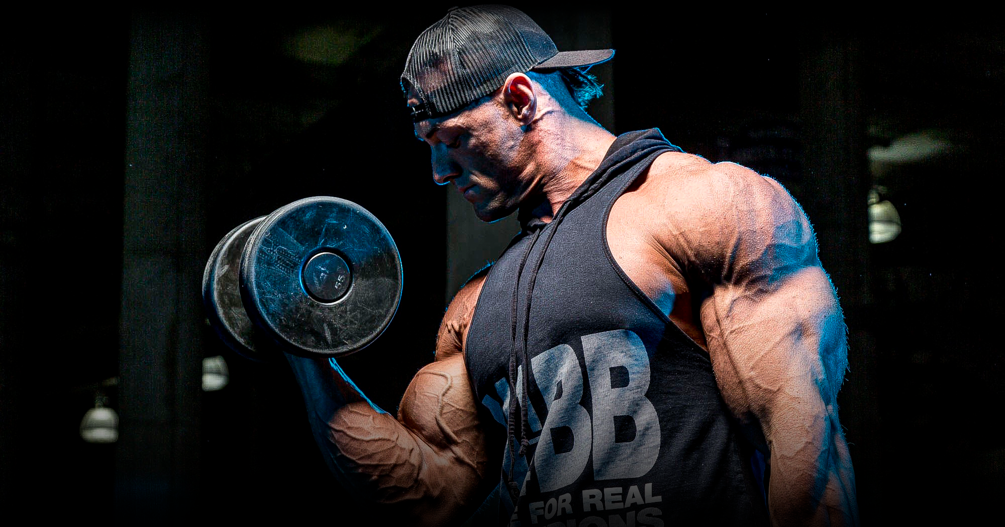 Bodybuilder performing a dumbbell curl in a gym, showing muscular arm definition and focused training.