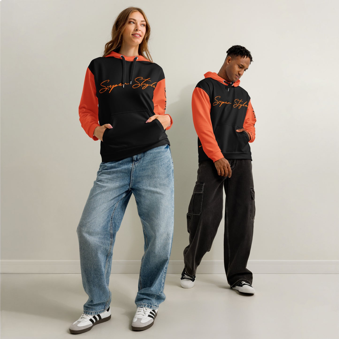 Two people wearing matching hoodies with orange sleeves and black bodies against a plain background